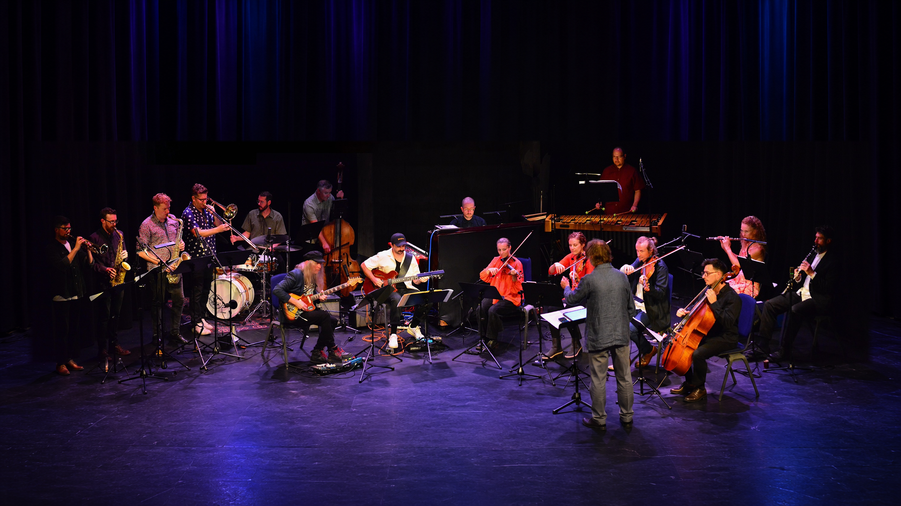 Stroma and The Jac performing together under blue and purple stage lights.